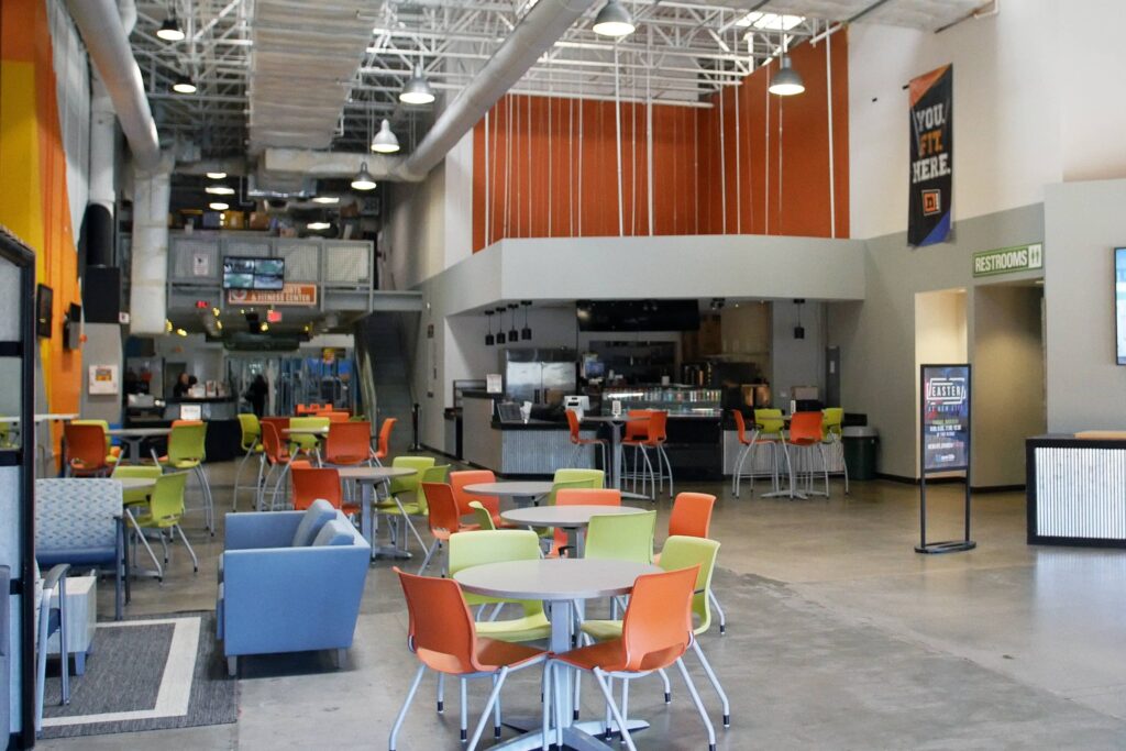Spacious lobby area with colorful seating, tables, and a cafe counter at The nZone, featuring a modern and welcoming design.