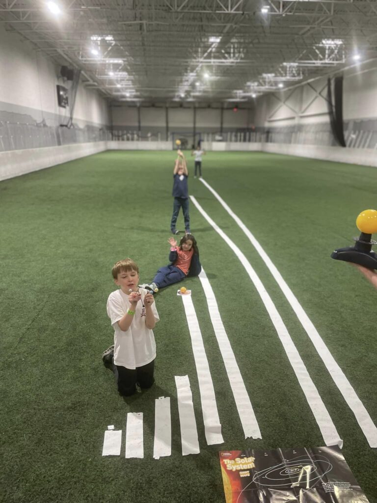 Four homeschool co-op students learn about the distances in the solar system on the nZone soccer field